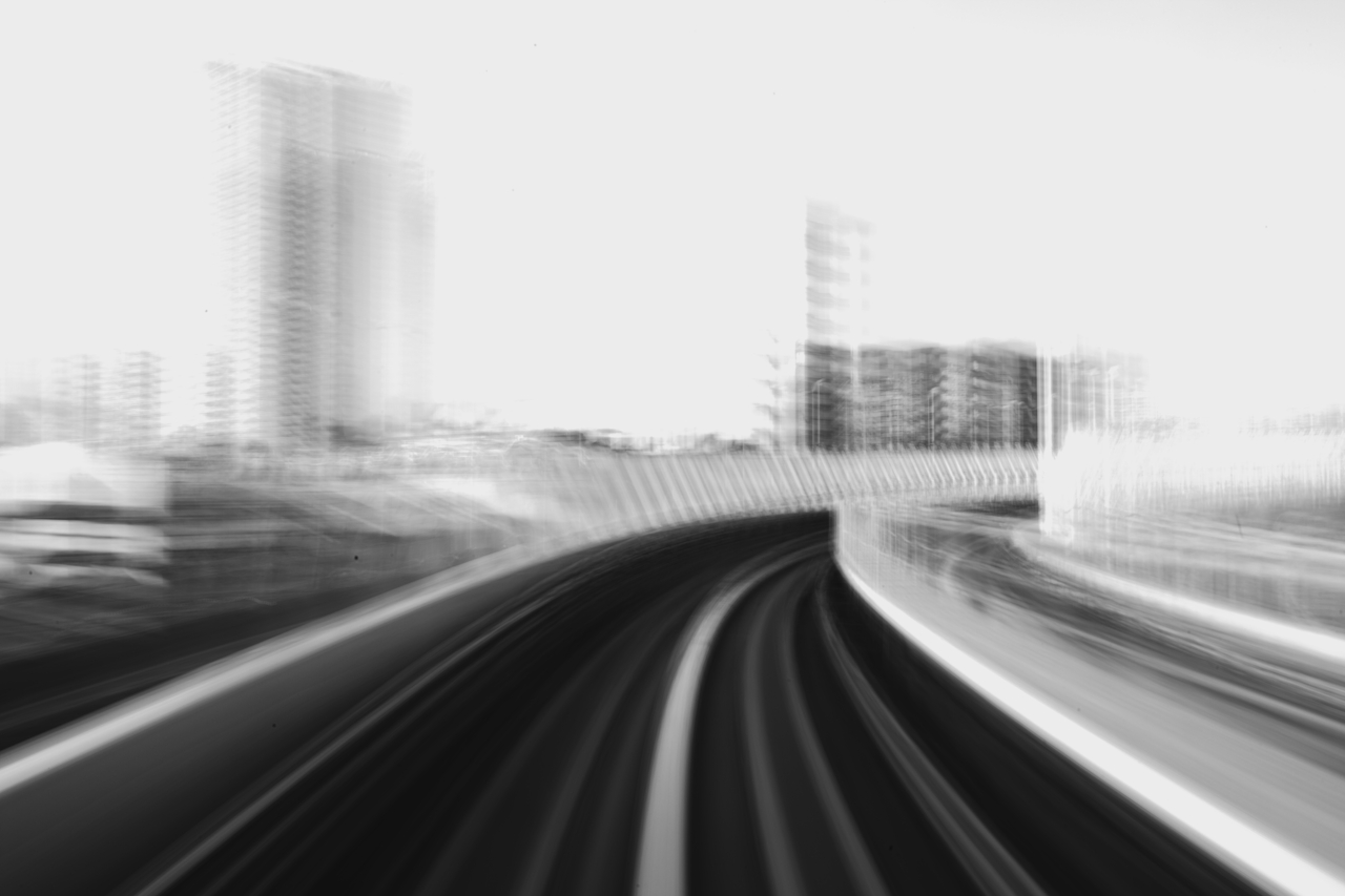 Young man with glasses and wavy hair wearing a black sweater sitting next to a beige wall with dried plants.